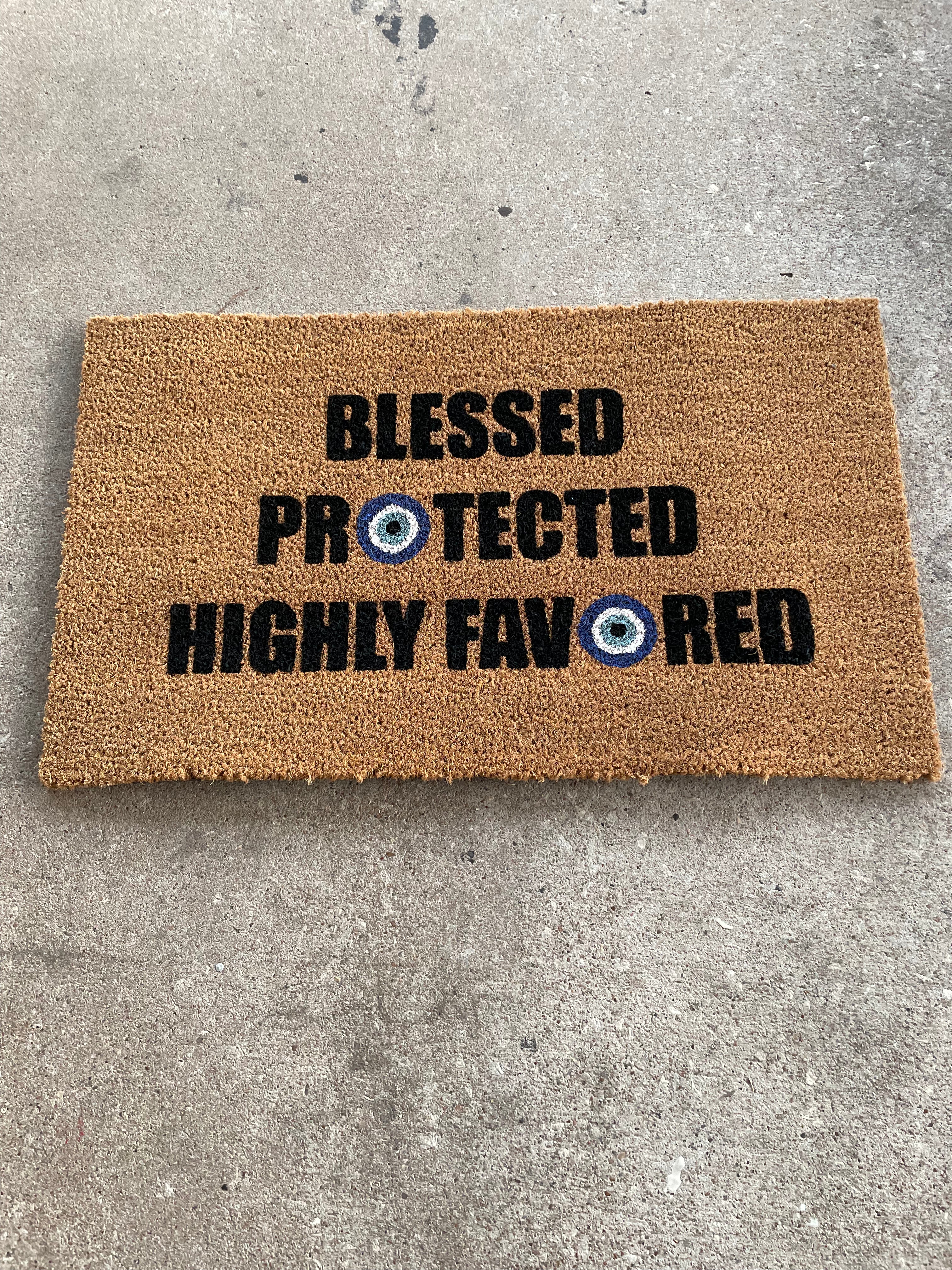 The Doormat District doormat with text "Blessed Protected Highly Favored" and Blue Evil Eyes