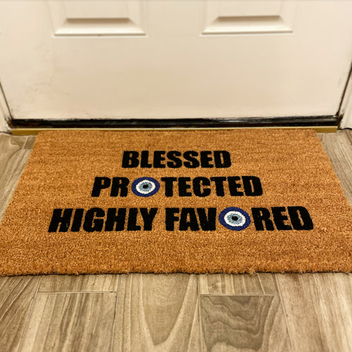The Doormat District with 'Blessed Protected Highly Favored' text and blue evil eye designs. 