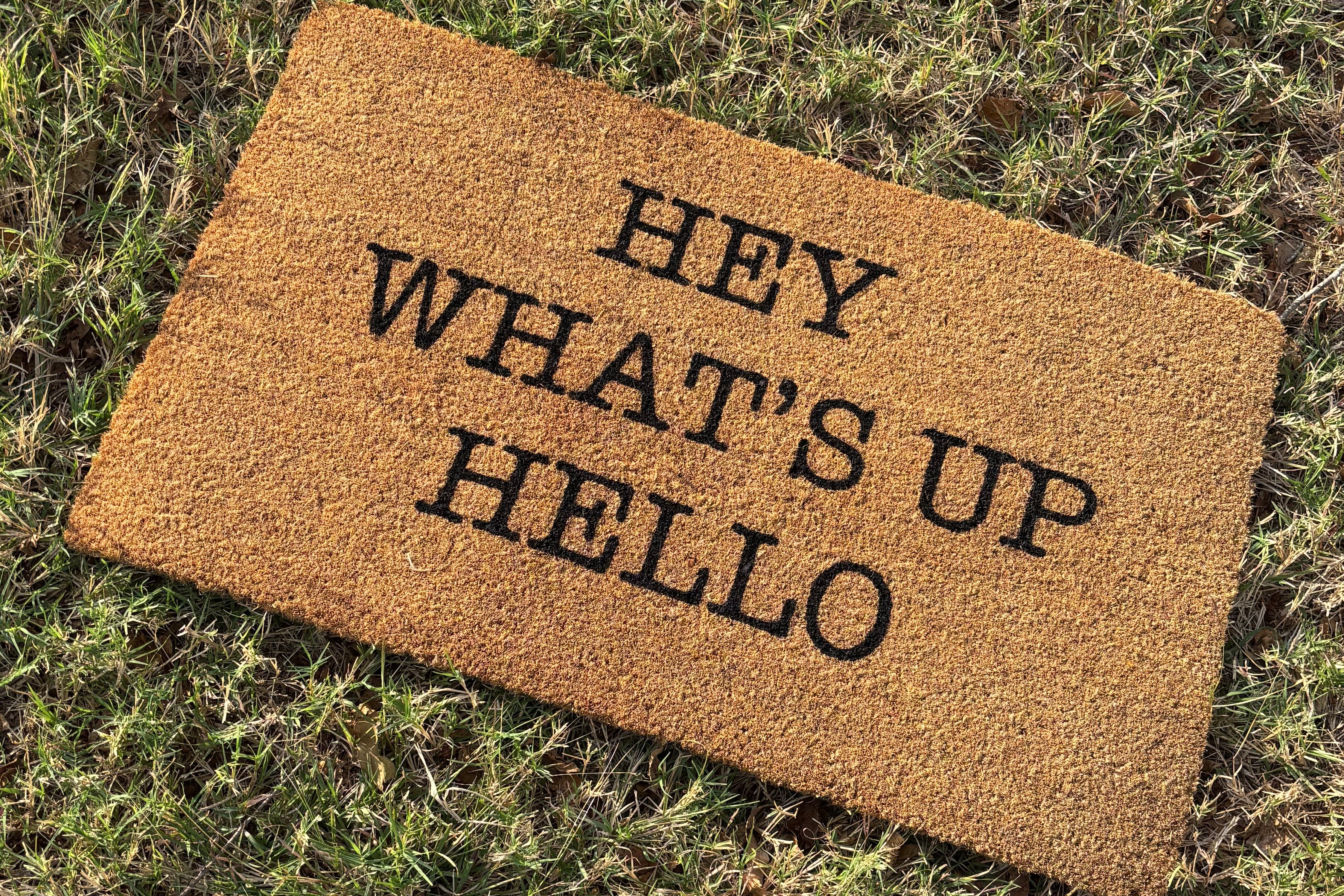 The Doormat District doormat with 'Hey What's Up Hello' text
