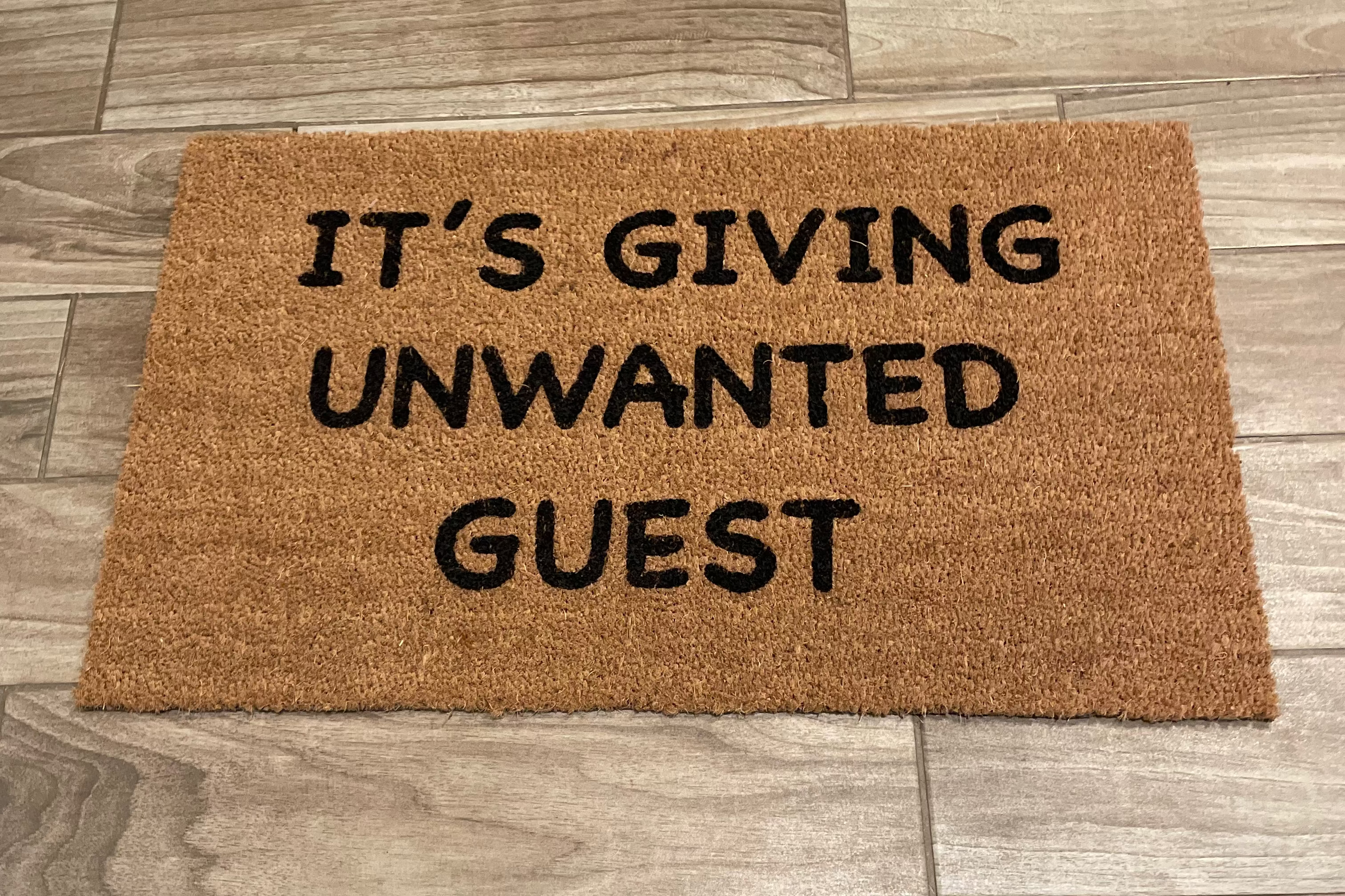 The Doormat District with text 'IT'S GIVING UNWANTED GUEST' 