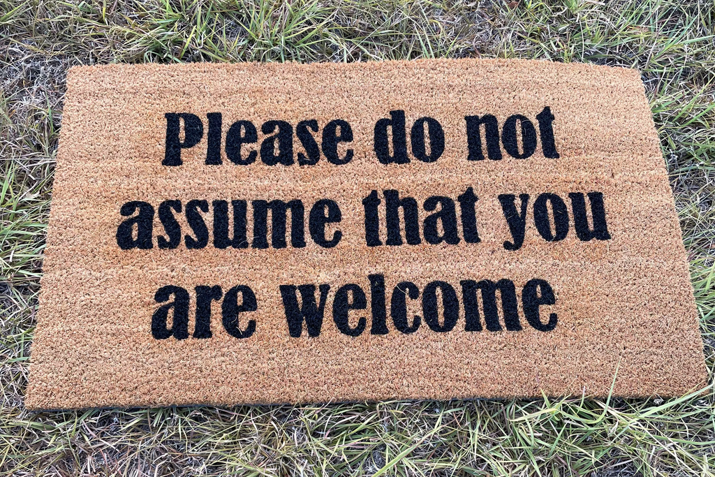 The Doormat District doormat with text "Please Do Not Assume That You Are Welcome" 