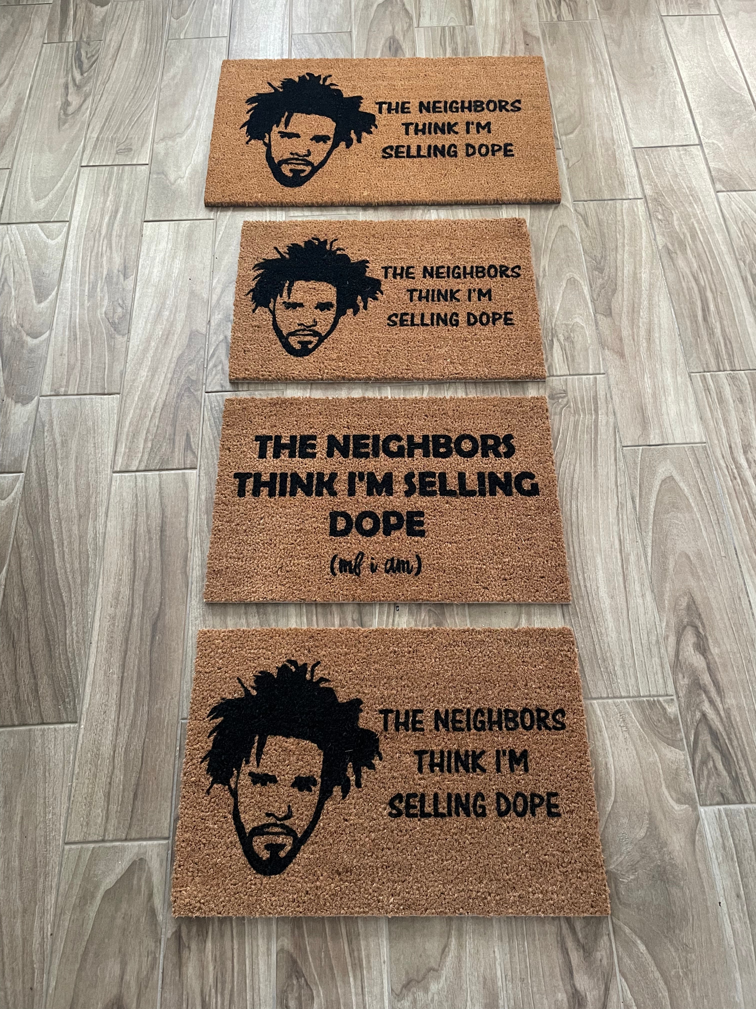 The Doormat District doormat with the text The Neighbors Think I'm Selling Dope With J. Cole Face Outline
